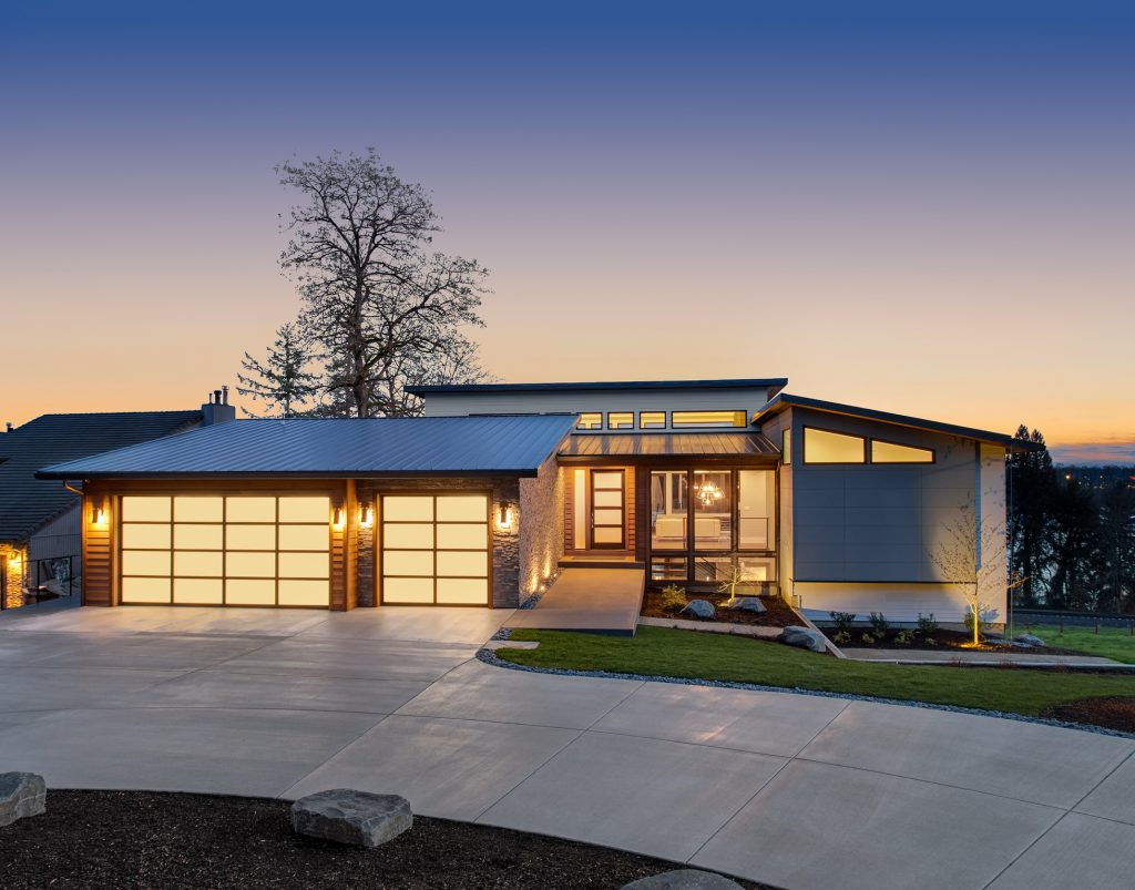 Modern home at dusk with all the lights on. 